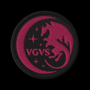May include: A black and pink embroidered patch featuring a dragon design and the text "VGVS" in the centre.