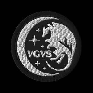 May include: A black and white embroidered patch featuring a crescent moon with a dragon inside. The text "VGVS" is in the centre of the patch.