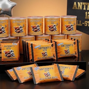 Pode incluir: Arranjo de embalagens e recipientes de lanches laranja e castanhos, rotulados como "Anthony's 12th All-Star Bash". Inclui balões em forma de estrela e um letreiro que diz "Reserve sua festa All-Star hoje!"
