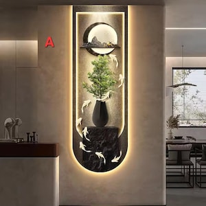 Könnte beinhalten: Wanddekoration mit einer schwarzen Vase mit einer grünen Pflanze, auf einem schwarzen Steinsockel. Das Kunstwerk umfasst ein kreisförmiges Element mit einer Berglandschaft und weißen Fischakzenten, alles in einem leuchtenden Rahmen.