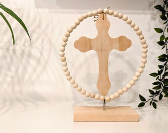 Träskulptur med en pärlring runt ett kors