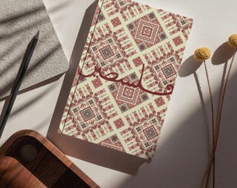 May include: A cream-colored journal with a red and gray geometric pattern and the word "سحر" written in red Arabic script.