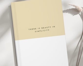 May include: A beige and white journal with the text "There is beauty in simplicity" printed on the front cover.