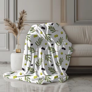 May include: White fleece throw blanket with a repeating pattern of green olive branches and black and green olives.
