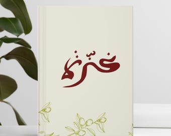 May include: A cream-colored journal with a red Arabic inscription that reads "Shukran" and a green olive branch design.