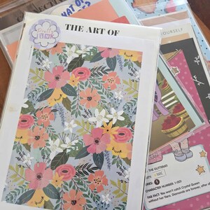 May include: A selection of art prints and ephemera, including floral designs and character cards. The main print displays a floral pattern in pink, orange, and white on a light blue backdrop. Other items include cards with text and illustrations.
