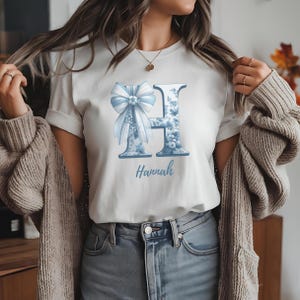 Chinoiserie Blue Toile letter with a delicate coquette bow, featuring an elegant vintage design in blue and white, perfect for monograms, personalized decor, and digital art projects.