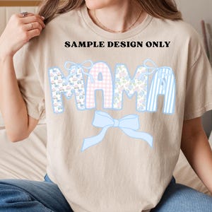 K&ouml;nnte beinhalten: Beiges T-Shirt mit dem Wort "MAMA" in dekorativer Schrift. Die Buchstaben sind mit floralen, Vichy- und gestreiften Mustern in Pastellfarben verziert, darunter eine hellblaue Schleife. Der Text "SAMPLE DESIGN ONLY" steht &uuml;ber dem Wort "MAMA".
