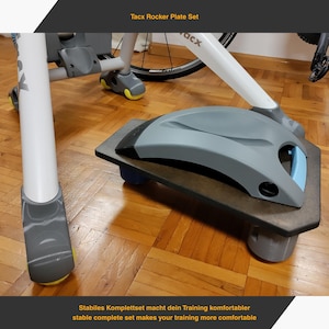 Könnte beinhalten: Ein Tacx Rocker Plate Set für das Indoor-Cycling. Das Set besteht aus einer grauen Wippenplatte mit schwarzem Rand, einer grauen Stützstruktur und einem Fahrrad. Der Text "Tacx Rocker Plate Set" ist sichtbar.