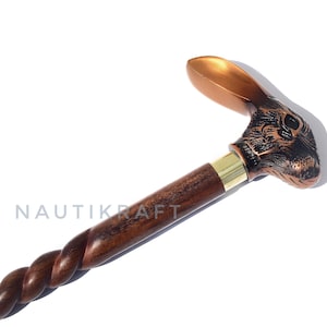 Può includere: Bastone da passeggio decorativo con manico a testa di coniglio in bronzo e fusto in legno intrecciato marrone scuro. Il bastone presenta un collare in ottone e la parola "NAUTIKRAFT" è stampata sul fusto.