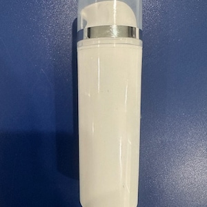 Może przedstawiać: Biała plastikowa butelka z przezroczystą plastikową pompką. Butelka jest pusta i ma srebrną taśmę wokół pompki.