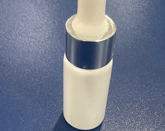 May include: A white glass bottle with a silver lid and a white dropper top. The bottle is on a blue surface.