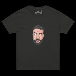 Könnte beinhalten: Dunkelgraues T-Shirt mit einer stilisierten Illustration eines Mannesgesichts mit Bart und geschlossenen weißen Augen. Die Grafik ist auf dem T-Shirt zentriert. Das T-Shirt hat einen Rundhalsausschnitt und kurze Ärmel.