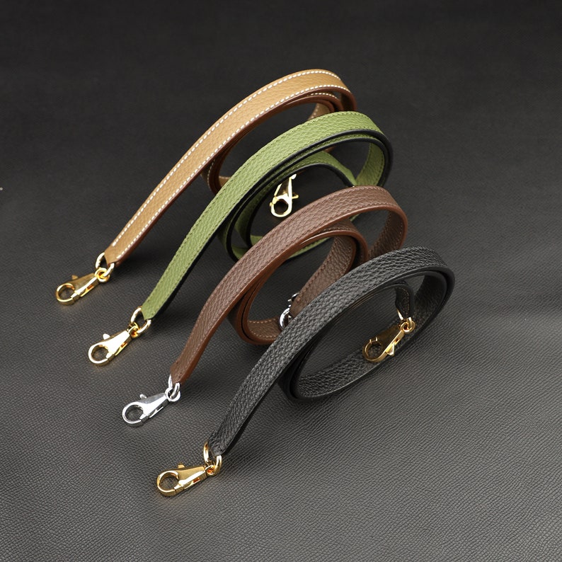 May include: Four leather straps with gold-toned clasps. The straps are in different colors: brown, green, tan, and black.