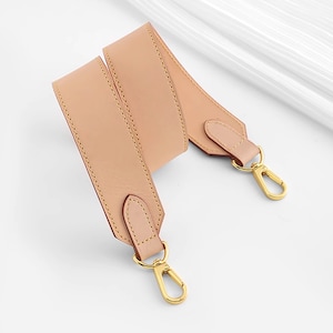 May include: A light brown leather strap with gold metal clasps. The strap is folded in half and the clasps are visible at both ends.