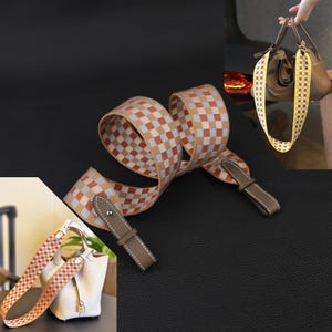 May include: A checkered pattern bag strap in shades of brown, orange, and blue. The strap has brown leather ends with white stitching. The image also shows the strap attached to a white and brown handbag.