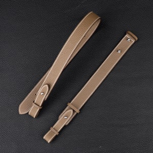 Peut inclure: Deux lani&egrave;res en cuir marron avec des coutures blanches et des ferrures m&eacute;talliques argent&eacute;es. Les lani&egrave;res sont de longueurs diff&eacute;rentes et ont des styles de boucles diff&eacute;rents.