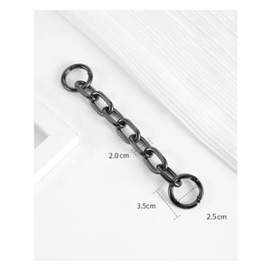 Puede incluir: Cadena de metal negro con dos anillos unidos. La cadena mide 3,5 cm de largo, los anillos tienen un diámetro de 2 cm y 0,75 cm.