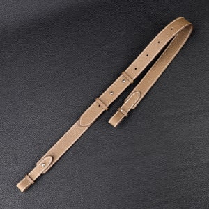 Peut inclure: Une sangle en cuir beige avec des coutures blanches et des ferrures argent&eacute;es. La sangle est con&ccedil;ue pour un sac ou un autre accessoire.