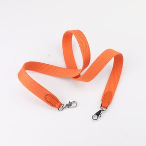 May include: Orange canvas shoulder strap with silver hardware and leather accents.