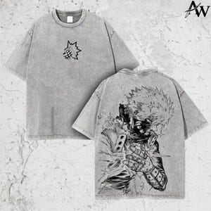 May include: Gray t-shirt featuring a graphic of an anime character on the back and a small emblem on the front. The shirt has a crew neck and short sleeves. The shirt is made of a soft, textured fabric.