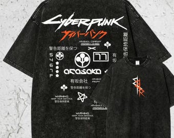 May include: Two black oversized t-shirts with a Cyberpunk design. The larger shirt displays the word "Cyberpunk" in white and red Japanese text, plus graphic elements and text. A smaller version of the shirt is also shown.