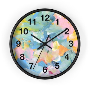 Puede incluir: Reloj de pared redondo con marco negro. La esfera presenta un diseño abstracto con pinceladas en tonos azules, rosas, amarillos y naranjas. Las manecillas y los números negros completan el diseño. Una pieza decorativa para cualquier habitación.