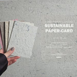 K&ouml;nnte beinhalten: Eine Hand h&auml;lt einen Stapel nachhaltiger Papierkarten in verschiedenen Farben, darunter Rosa, Beige und Grau. Die Karten bestehen aus recycelten Textilfasern und sind mit pflanzlichem Kleber gebunden. Der Text lautet "HANDMADE IN SCOTLAND SUSTAINABLE PAPER-CARD".