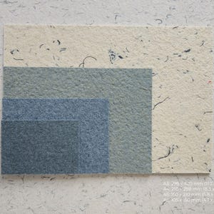 K&ouml;nnte beinhalten: Verschiedene Gr&ouml;&szlig;en von strukturierten Papierb&ouml;gen in Blau- und Cremet&ouml;nen. Formate: A3 (298 x 420 mm), A4 (210 x 298 mm), A5 (150 x 210 mm) und A6 (105 x 150 mm). Das Papier hat sichtbare Fasern und wirkt handgefertigt.