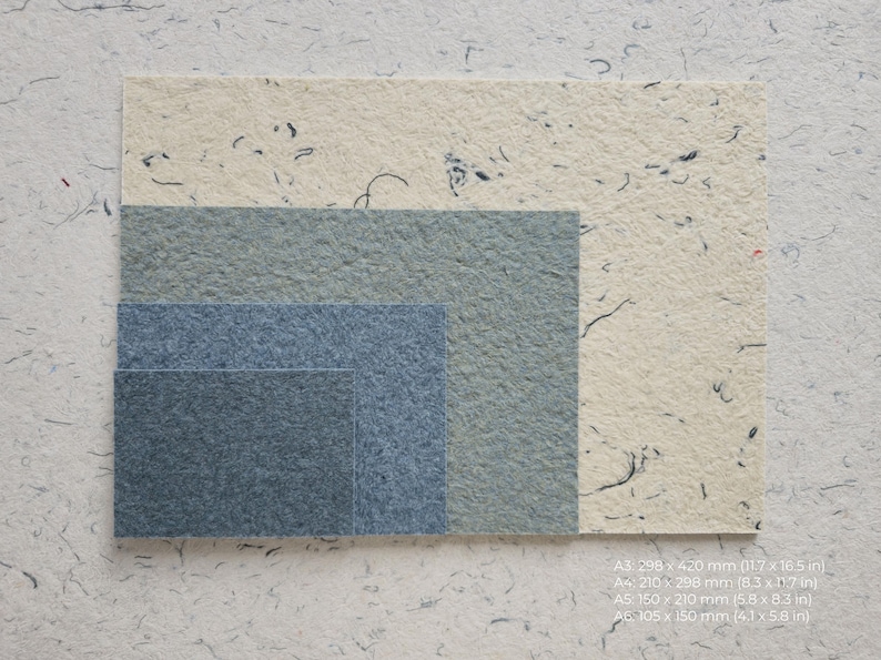 K&ouml;nnte beinhalten: Verschiedene Gr&ouml;&szlig;en von strukturierten Papierb&ouml;gen in Blau- und Cremet&ouml;nen. Formate: A3 (298 x 420 mm), A4 (210 x 298 mm), A5 (150 x 210 mm) und A6 (105 x 150 mm). Das Papier hat sichtbare Fasern und wirkt handgefertigt.