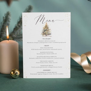 Puede incluir: Un menú navideño con una ilustración de acuarela de un árbol de Navidad decorado. El menú incluye una ensalada de rúcula navideña, solomillo Wellington, puré de patatas, brócoli asado, zanahorias tricolores, pan casero y crema catalana de jengibre.