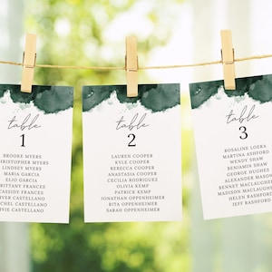 May include: Three white cards with green watercolor accents and black text. The cards are labeled "table 1", "table 2", and "table 3" and list names for each table.