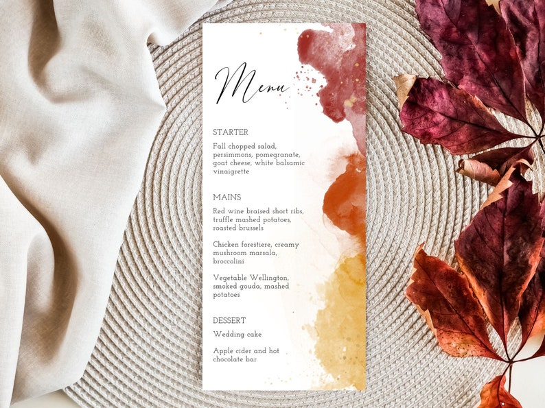 May include: A fall-themed menu with watercolor splashes in shades of red, orange, and yellow. The menu lists a starter, main courses, and dessert options. The text reads: "Menu, Starter, Fall chopped salad, persimmons, pomegranate, goat cheese, white balsamic vinaigrette, Mains, Red wine braised short ribs, truffle mashed potatoes, roasted brussels, Chicken forestiere, creamy mushroom marsala, broccolini, Vegetable Wellington, smoked gouda, mashed potatoes, Dessert, Wedding cake, Apple cider and hot chocolate bar."