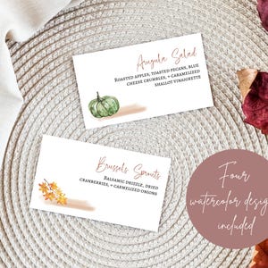 K&ouml;nnte beinhalten: Vier Aquarelldesigns f&uuml;r Lebensmitteletiketten mit Herbstmotiven. Die Designs beinhalten einen gr&uuml;nen K&uuml;rbis, Herbstbl&auml;tter und Text, der "Rucola-Salat" und "Rosenkohl" lautet.