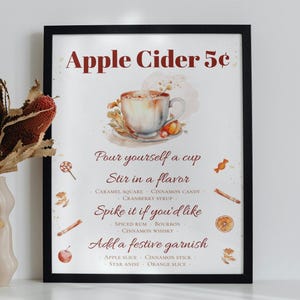 May include: A printable sign for a fall-themed drink stand. The sign features a watercolor illustration of a cup of apple cider with fall-themed garnishes. The text on the sign reads "Apple Cider 5&cent;" and includes instructions for making the drink, such as "Pour yourself a cup", "Stir in a flavor", "Spike it if you'd like", and "Add a festive garnish".