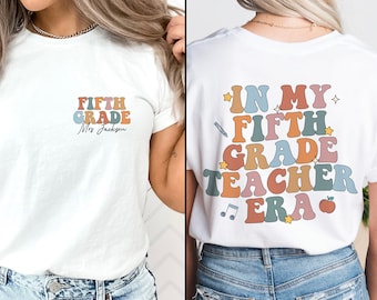 Peut inclure: T-shirt blanc avec un design rétro coloré qui dit "Cinquième année" sur le devant et "Dans mon ère d'enseignant de cinquième année" au dos.