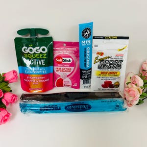 May include: A collection of sports nutrition items including a GoGo SqueeZ Active fruit pouch, a pink SaltStick FastChews packet, a Country Archer Mini Beef Stick, a pack of Extreme Sport Beans, and a blue Pedialyte Freezer Pop sleeve.