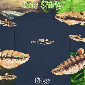 May include: Navy blue kids' shirt featuring a small fish graphic. The shirt has the words "Kids Shirts" in green and the word "Navy" in white. The shirt is surrounded by images of fish.