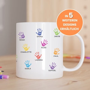 Könnte beinhalten: Weiße Keramiktasse mit bunten Handabdruck-Designs und Namen wie Noah, Emma, Jakob, Charlotte, Elias, Paul, Larissa, Karla und Samuel. Der Text "IN 5 WEITEREN DESIGNS ERHÄLTLICH" befindet sich auf einem leuchtend orangenen Kreis.
