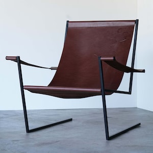 May include: A brown leather chair with a black metal frame. The chair has a simple, modern design.