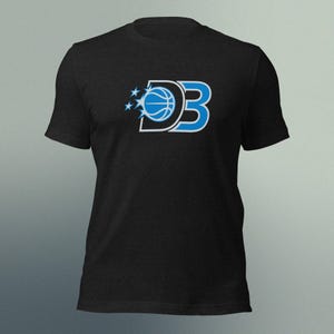 May include: Black t-shirt featuring a basketball-themed logo. The logo includes the letters "DB" in a stylized font, with a basketball incorporated into the "D" and three stars. The design is in shades of blue and white.