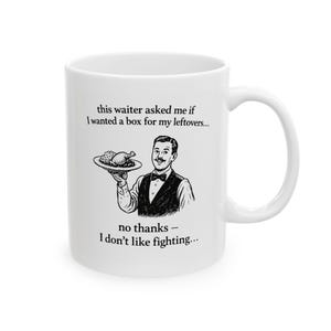 May include: White ceramic mug with a black and white illustration of a waiter holding a plate of food. Text on the mug reads, "this waiter asked me if I wanted a box for my leftovers... no thanks - I don't like fighting..."