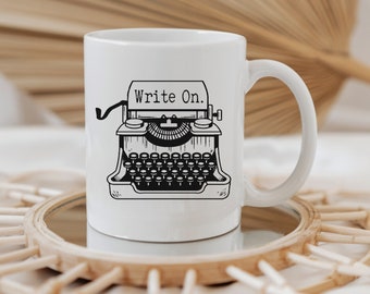 May include: White ceramic mug with a black and white illustration of a vintage typewriter. The text "Write On." is printed on the mug.