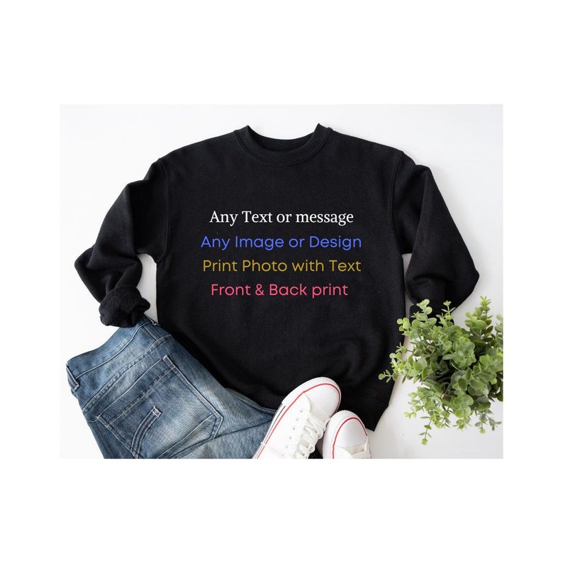 May include: A black long-sleeve crewneck sweatshirt featuring white, blue, yellow, and red text that reads: Any Text or message, Any Image or Design, Print Photo with Text, Front & Back print. The sweatshirt is displayed with blue jeans.