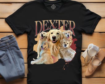May include: Black t-shirt featuring a graphic of five golden retriever dogs with the name "DEXTER" in a stylized font. The shirt is displayed on a wooden surface with a pair of blue jeans and shoes.