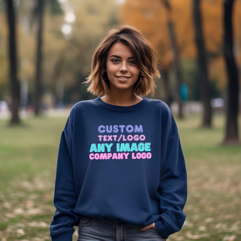 May include: A navy blue long-sleeve sweatshirt featuring the text CUSTOM TEXT/LOGO, ANY IMAGE, and COMPANY LOGO printed in stacked lines using light purple, cyan, and pink colors on the front center of the garment.