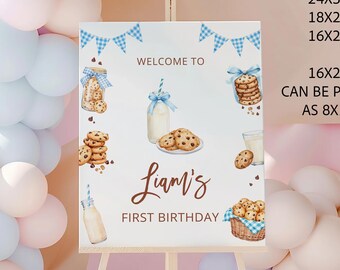 Op de afbeelding: Welkom op Liams eerste verjaardagsbord met een blauw-wit geruit lint, flessen melk, koekjes en een mand met koekjes. Het bord staat op een houten ezel en is omringd door pastelblauwe en roze ballonnen.