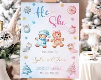 May include: A gender reveal sign on an easel. The sign has a blue and pink gradient background with the words "He or She". It features gingerbread people and holiday-themed illustrations. The sign reads "Welcome to Sophia and James, Gender Reveal, November 25th 20xx."