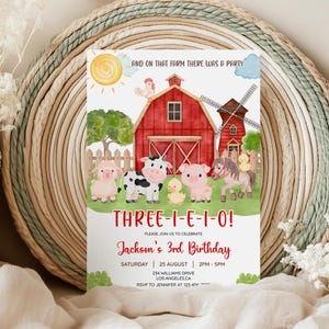 以下が含まれることがあります： 赤い納屋、風車、漫画の動物が描かれた、農場をテーマにした誕生日招待状。「THREE-I-E-I-O！」と「ジャクソンの3歳の誕生日」と書かれています。招待状には日付、時間、場所が含まれています。