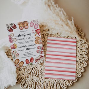 May include: A white Christmas pyjama party invitation with a red and white striped back. The front features a festive illustration of reindeer, slippers, popcorn, and candy canes. The text reads "Please join us for a Christmas Pyjama Party. Put on your fav jammies and join us for a festive fun! Hosted by the Andersons. Saturday | 23 | December. At 2:00 PM. 254 Williams Drive. Los Angeles, CA. RSVP to Jennifer at 415-449-7890."
